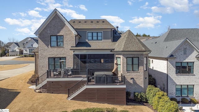 back of property with a deck, brick siding, stairway, and a shingled roof