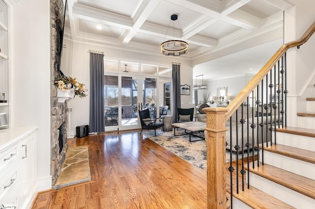 interior space with coffered ceiling, a fireplace, wood finished floors, stairs, and beam ceiling