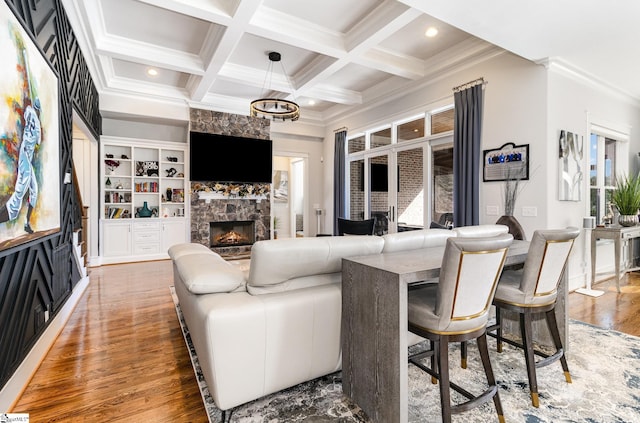 living area with beam ceiling, recessed lighting, a stone fireplace, wood finished floors, and coffered ceiling