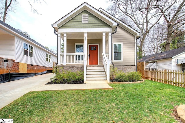 view of front of property featuring a porch, a front yard, fence, and brick siding