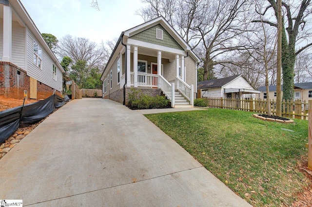 view of front of home with a front yard, covered porch, and fence