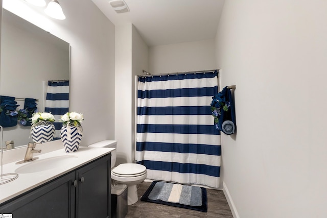 bathroom featuring toilet, a shower with shower curtain, wood finished floors, visible vents, and vanity