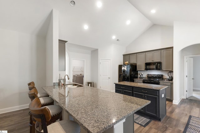 kitchen featuring a breakfast bar, a center island, a peninsula, black appliances, and a sink