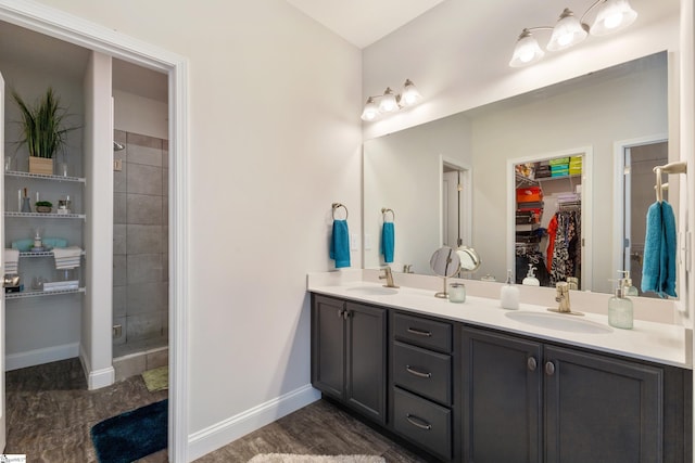 full bath with double vanity, a spacious closet, baseboards, and a sink