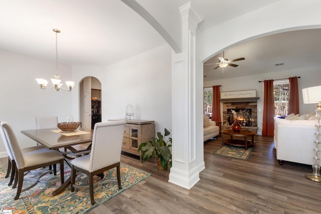 dining area featuring ceiling fan with notable chandelier, arched walkways, a healthy amount of sunlight, and wood finished floors