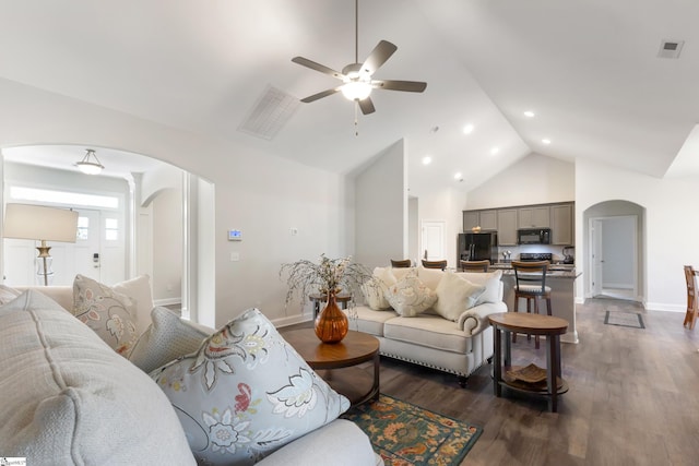 living room with visible vents, arched walkways, dark wood finished floors, baseboards, and high vaulted ceiling