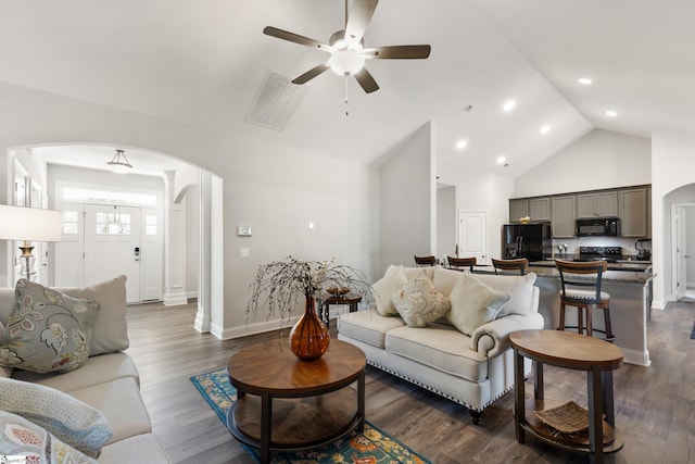 living room featuring dark wood-type flooring, arched walkways, visible vents, and high vaulted ceiling