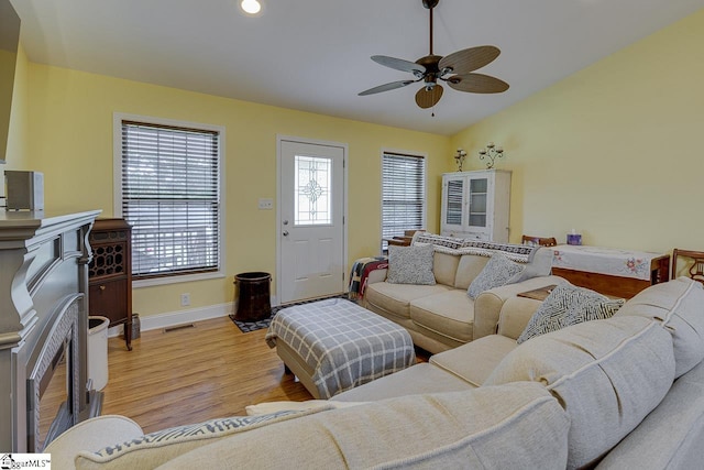 living area featuring baseboards, visible vents, lofted ceiling, light wood-style floors, and a fireplace