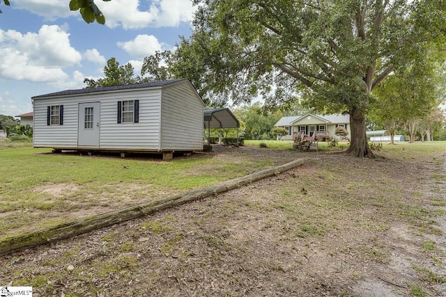 exterior space featuring a detached carport, an outdoor structure, and a front yard