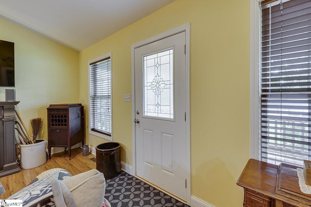 entryway featuring lofted ceiling, baseboards, and wood finished floors