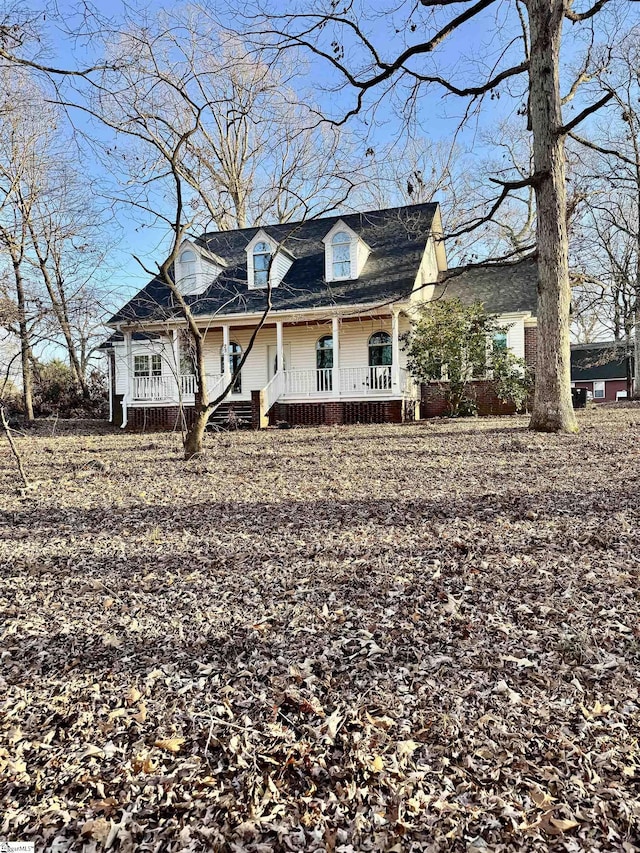 cape cod house featuring covered porch