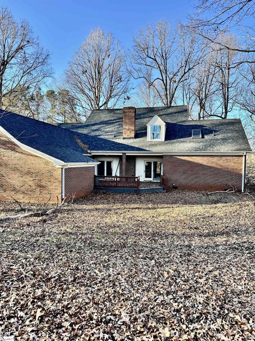 rear view of property with brick siding and a chimney