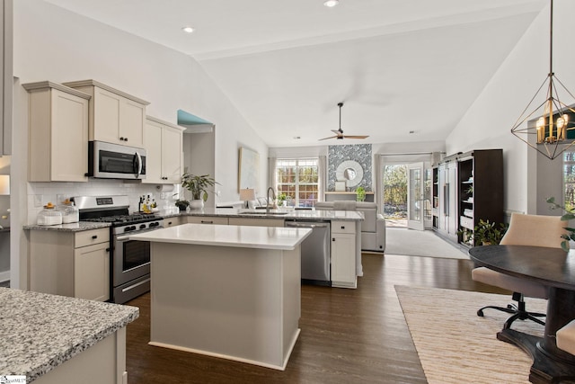 kitchen with lofted ceiling, stainless steel appliances, a peninsula, a sink, and open floor plan