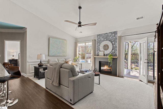 living area featuring visible vents, ceiling fan, wood finished floors, vaulted ceiling, and a fireplace