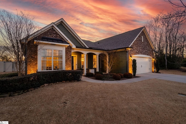 craftsman-style home featuring driveway, a garage, roof with shingles, a yard, and brick siding