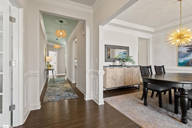 entryway featuring baseboards, ornamental molding, wood finished floors, and a notable chandelier