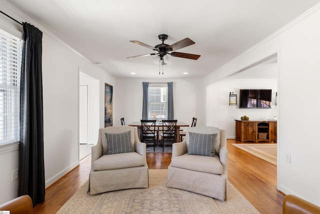 sitting room with a ceiling fan, ornamental molding, and wood finished floors