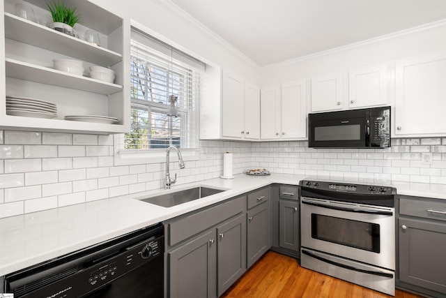 kitchen featuring crown molding, gray cabinets, decorative backsplash, a sink, and black appliances