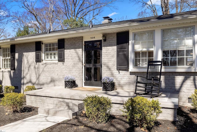 property entrance with brick siding, crawl space, and a chimney