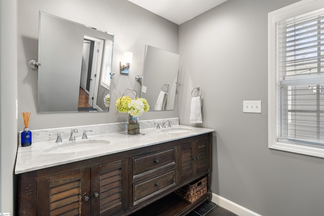 bathroom featuring tile patterned flooring, a sink, baseboards, and double vanity