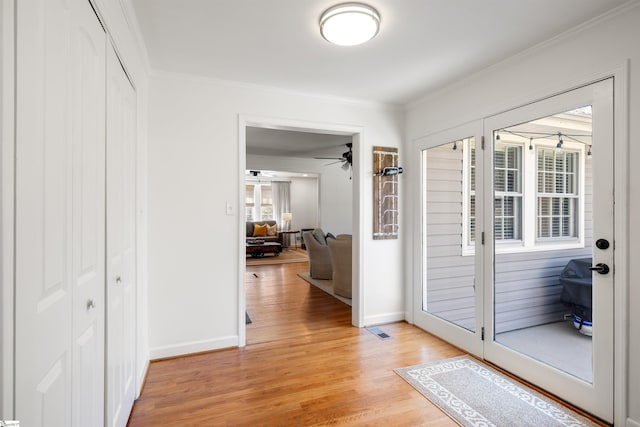 entryway featuring light wood-style floors, visible vents, ornamental molding, and baseboards