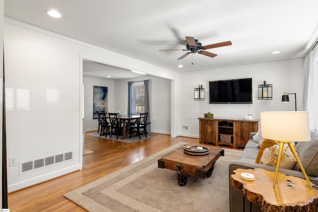living room featuring light wood finished floors, recessed lighting, visible vents, ornamental molding, and baseboards