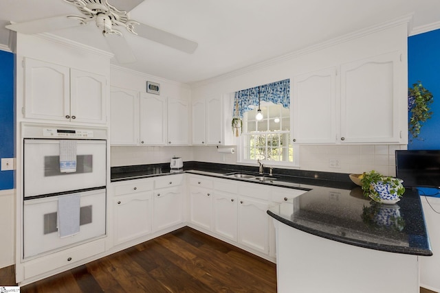 kitchen featuring white cabinets, dark wood finished floors, white double oven, and a peninsula