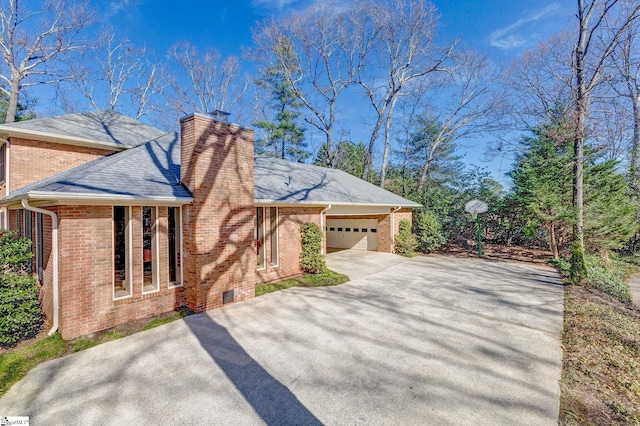 view of property exterior featuring an attached garage, brick siding, concrete driveway, roof with shingles, and a chimney