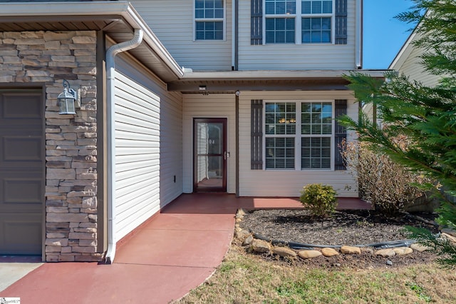 property entrance with an attached garage and stone siding