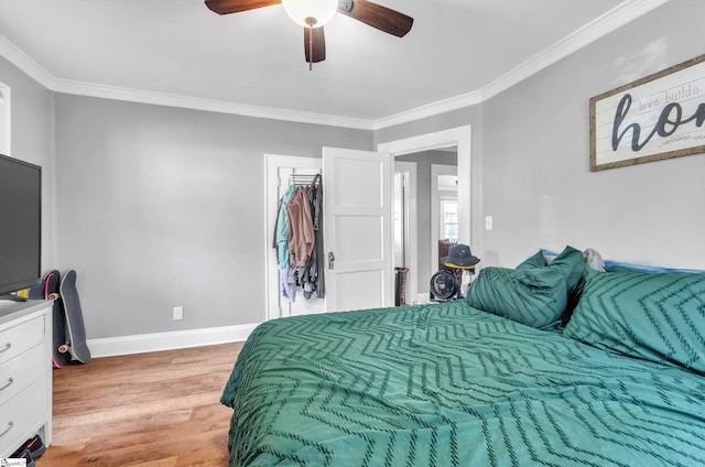 bedroom with light wood-type flooring, a ceiling fan, baseboards, and crown molding