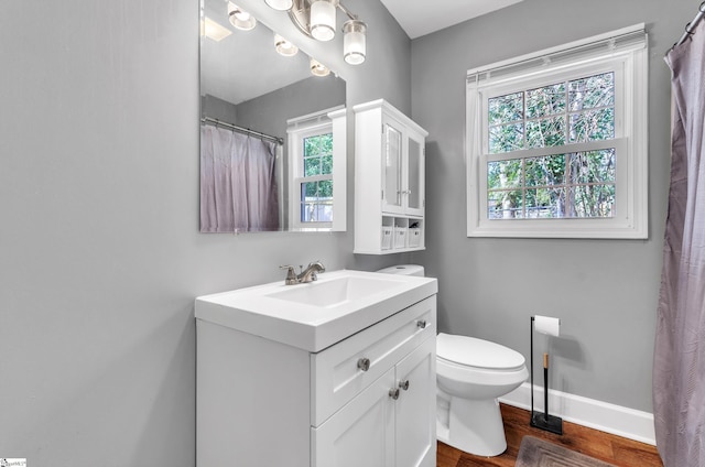 full bath with toilet, baseboards, wood finished floors, and vanity