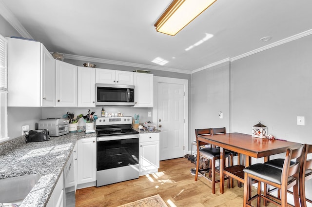 kitchen featuring light wood finished floors, appliances with stainless steel finishes, white cabinetry, and crown molding