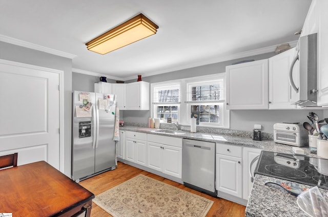 kitchen with stainless steel appliances, a sink, white cabinets, ornamental molding, and light wood finished floors