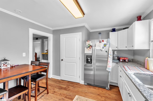 kitchen featuring light wood-style flooring, white cabinetry, light countertops, ornamental molding, and stainless steel fridge