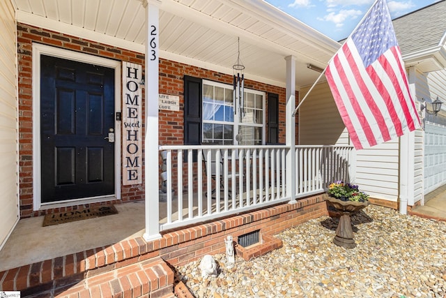 property entrance featuring covered porch and brick siding