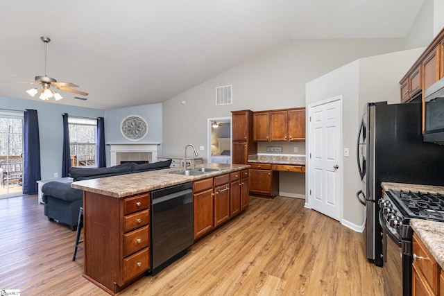 kitchen featuring light wood finished floors, visible vents, open floor plan, a sink, and black appliances