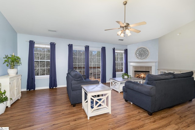 living area with lofted ceiling, a fireplace, baseboards, and wood finished floors