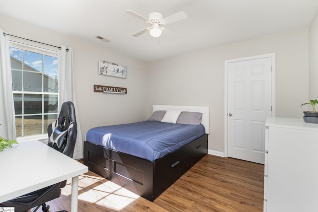 bedroom featuring a ceiling fan, visible vents, baseboards, and wood finished floors