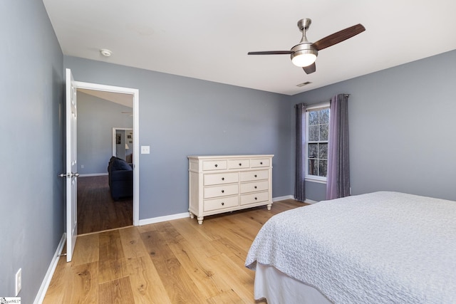 bedroom with light wood finished floors, a ceiling fan, visible vents, and baseboards