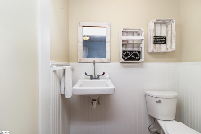 bathroom featuring a wainscoted wall, a sink, and toilet