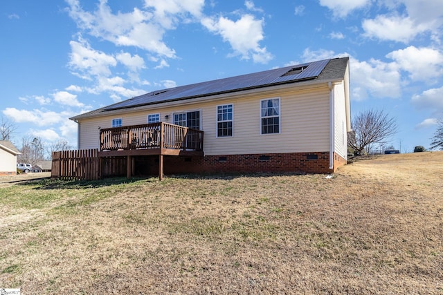 back of house with crawl space, a lawn, a deck, and solar panels