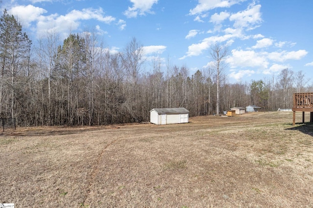 view of yard featuring an outbuilding, a storage unit, and a wooded view