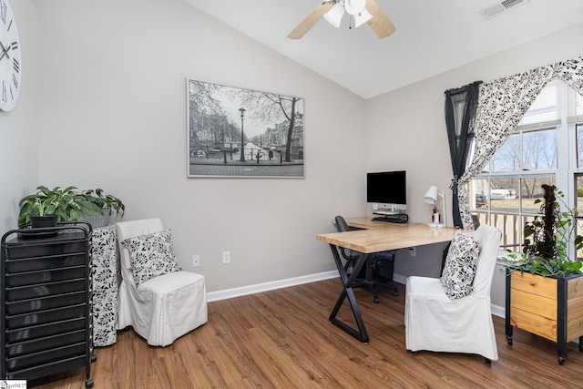 home office featuring visible vents, a ceiling fan, vaulted ceiling, wood finished floors, and baseboards