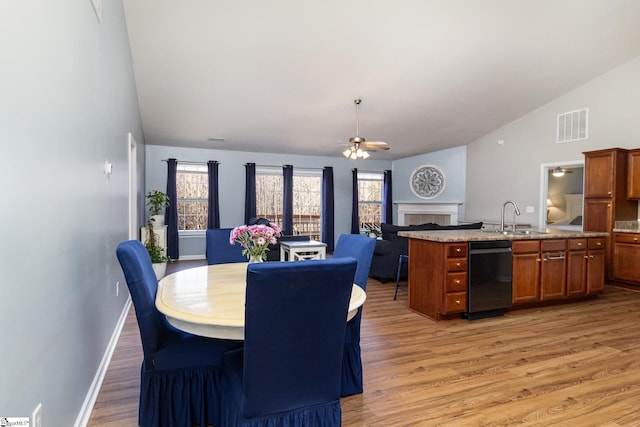 dining area featuring a fireplace, visible vents, ceiling fan, light wood-type flooring, and baseboards