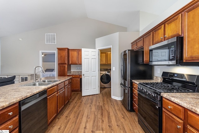 kitchen with stainless steel appliances, washer / clothes dryer, a sink, visible vents, and light wood finished floors