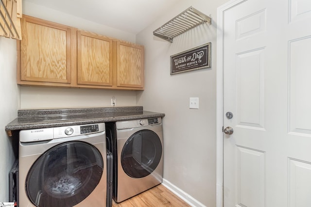 laundry room featuring cabinet space, light wood-style flooring, baseboards, and washer and clothes dryer