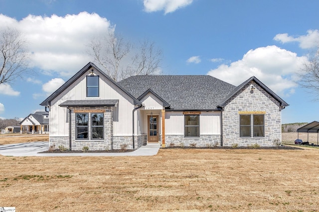 modern farmhouse style home with a shingled roof, stone siding, and a front lawn