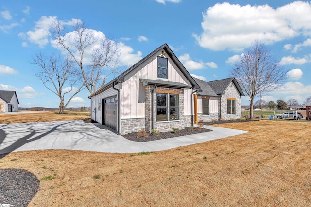 view of front of home featuring an attached garage, board and batten siding, a front yard, stone siding, and driveway