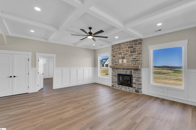 unfurnished living room with a fireplace, visible vents, beam ceiling, and wood finished floors