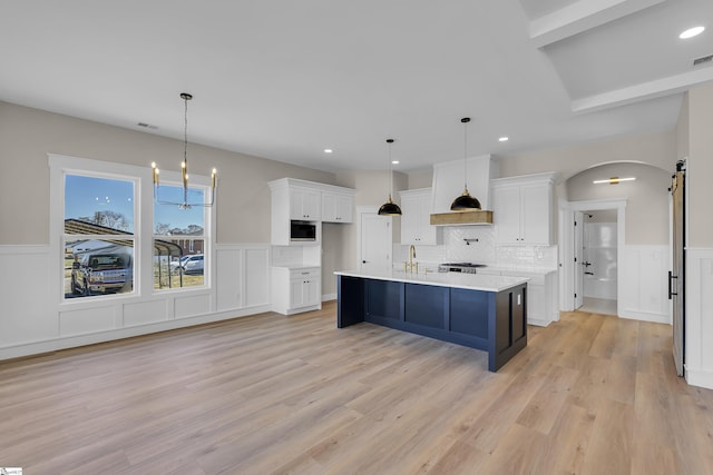 kitchen featuring arched walkways, a barn door, white cabinetry, and built in microwave